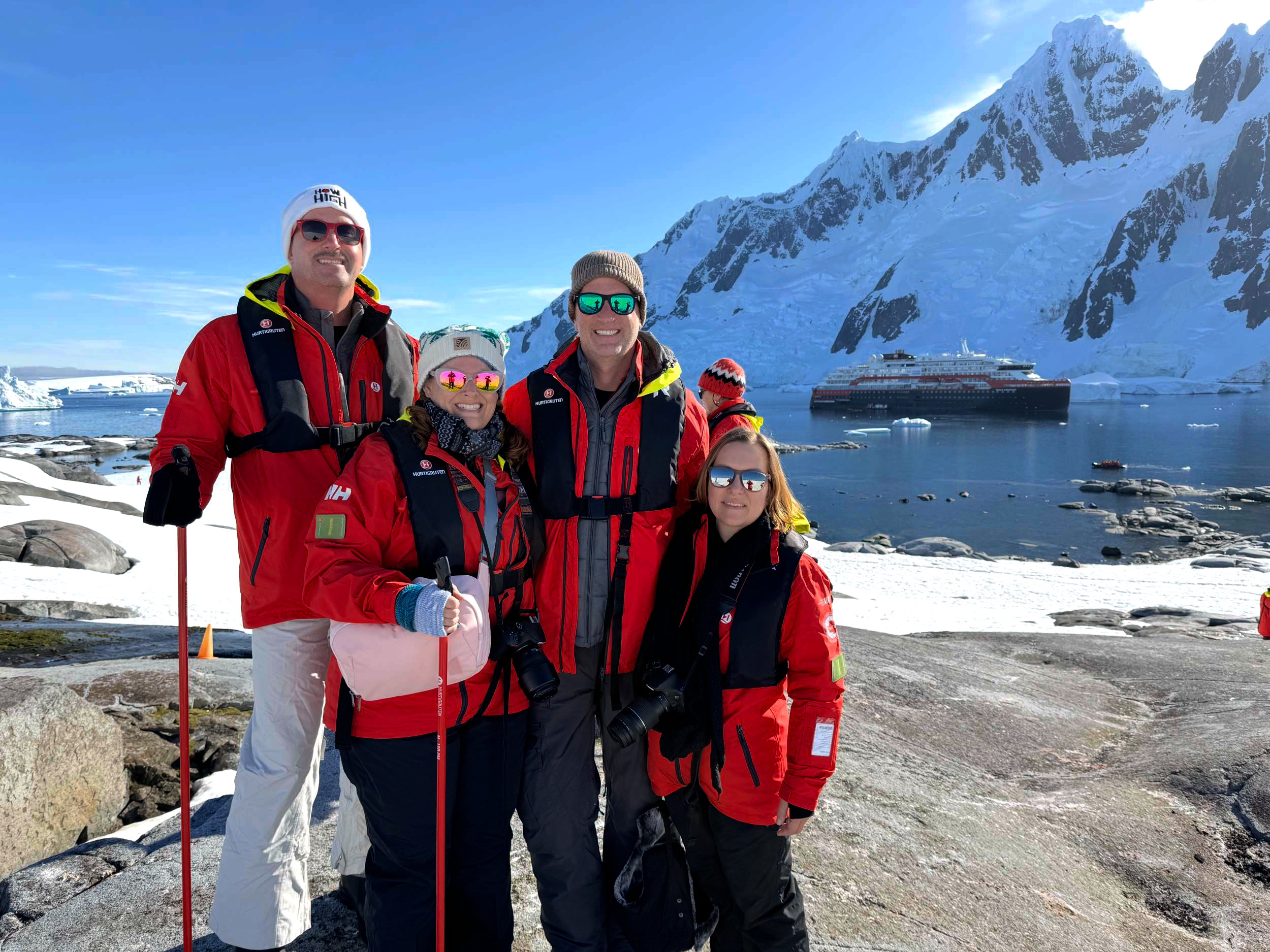 Keith, Niki and guests on a group expedition in Antarctica, with the expedition ship behind them